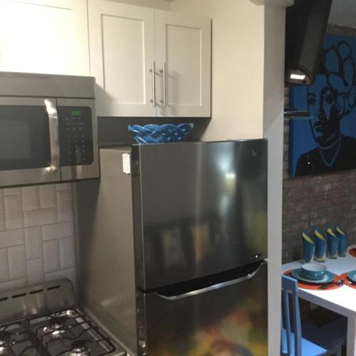 a kitchen with a stainless steel refrigerator and white cabinets at The Harlem Getaway in New York