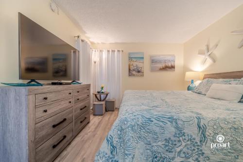 a bedroom with a bed and a dresser with a television at Hello Sunshine Steps To the Beach in Destin
