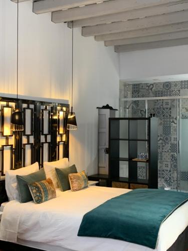 1 dormitorio con 1 cama blanca grande con detalles verdes en La Chambre Bleue Chipiona en Chipiona