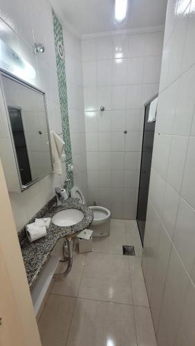 a bathroom with a sink and a tub and a mirror at Apto Cavalinho Branco in Águas de Lindoia