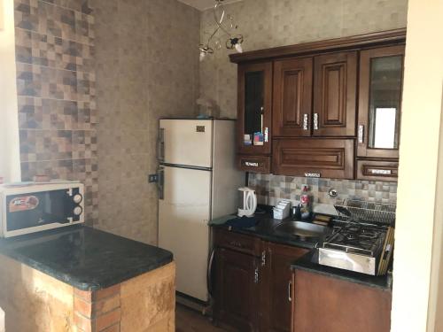 a kitchen with a white refrigerator and wooden cabinets at شاليه فندقي ڤيو البحر Ain sokhna-families& married only in Ain Sokhna