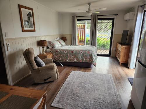 a bedroom with a bed and a chair and a window at Spencer Lane Cottage & Granny Flat in Stanthorpe