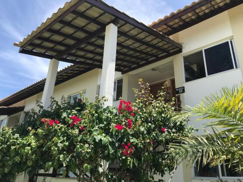 een huis met roze bloemen ervoor bij Apartamento Reserva Imbassaí quarto e sala 68m² in Mata de Sao Joao