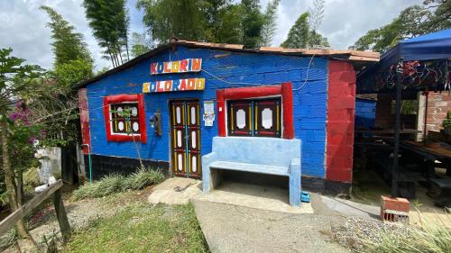 a blue and red building with a bench in front of it at La Kolorina hotel campestre in Jericó