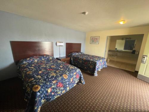 a hotel room with two beds and a mirror at Village Inn in Ada