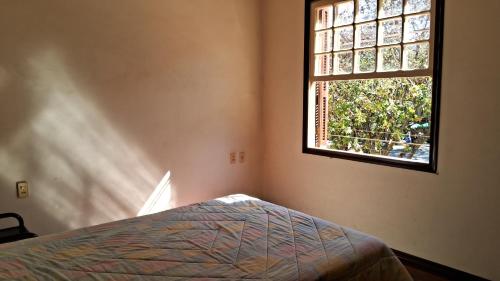 um quarto com uma cama e uma janela em Serra Negra Apartment em Serra Negra