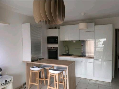 une cuisine avec des placards blancs et un îlot avec des tabourets de bar dans l'établissement Le Vallon, à Marseille