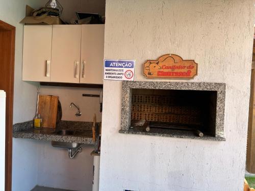 a kitchen with a fireplace with a sign on it at POUSADA ROSA e POESIA in Praia do Rosa