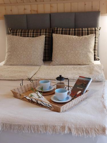 a tray with two coffee cups and a book on a bed at Domki Zew Natury in Lesko