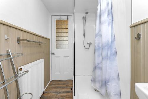 a bathroom with a shower and a white door at Marchmont Traditional Apartments in Edinburgh