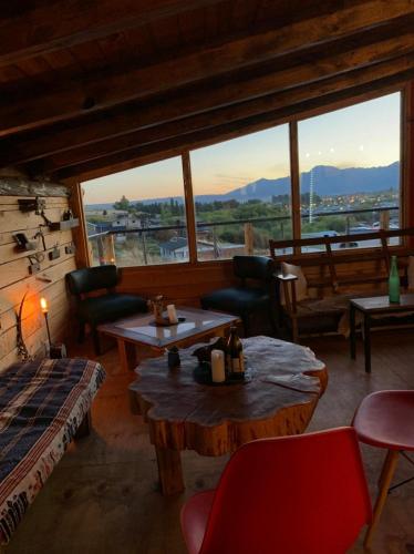 ein Wohnzimmer mit Tischen und Stühlen und einem großen Fenster in der Unterkunft Hostel Luan Posada de Montaña in Trevelín