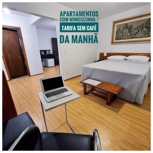 a room with a bed and a table with a laptop at Hotel Germânia in Joinville