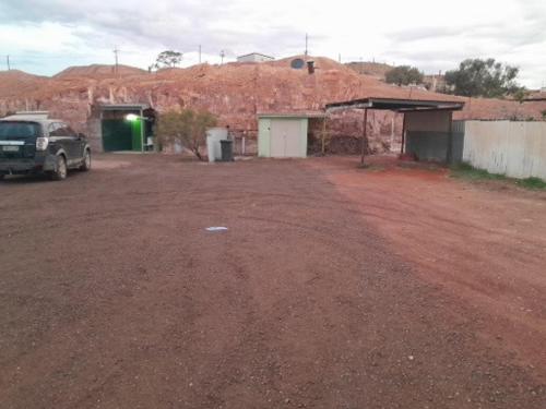 a dirt parking lot with a truck parked in front of a building at Green Opal in Coober Pedy