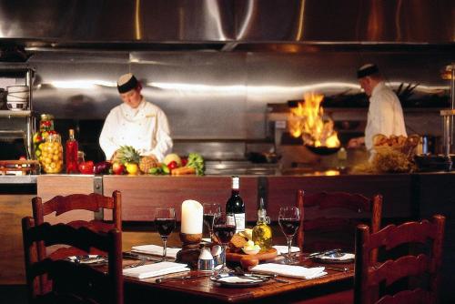two chefs in a kitchen preparing food in a restaurant at Rendezvous Heritage Hotel Queenstown in Queenstown