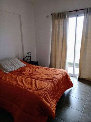 1 dormitorio con cama de color naranja y ventana en Departamento 2 ambientes en La Plata