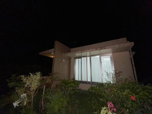 a small house with a lit up window at night at 憩いの場　ただいま〜 in Nago