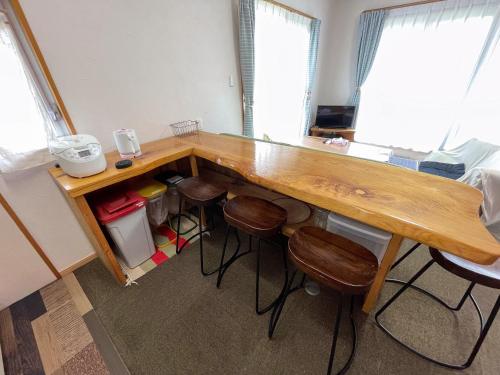 a kitchen with a wooden counter with stools under it at 憩いの場　ただいま〜 in Nago
