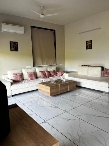 a living room with white couches and a screen at Serene stay in the lap of Nature in Ahmedabad