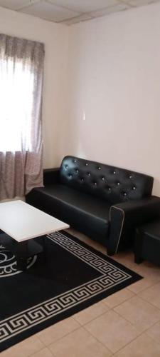 een woonkamer met een zwarte leren bank en een tafel bij Cherating Damai Guest House in Cherating