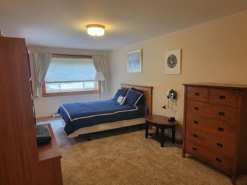 a bedroom with a blue bed and a dresser at Kenway Ranch in Southwest Harbor