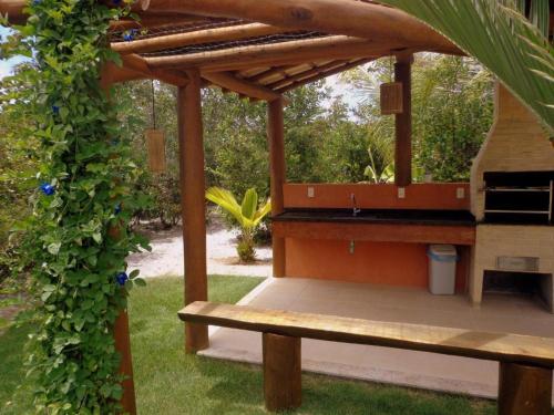 a wooden bench under a pergola in a garden at Breeze 09 Imbassaí in Imbassai