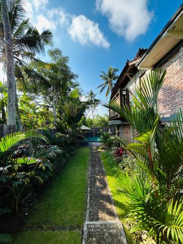 a garden in front of a house with palm trees at Puri Sundaram Villa in Ubud