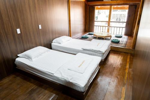 twee bedden in een kleine kamer met een raam bij Odyssey Hostel, Tours & Motorbikes Rental in Ha Giang