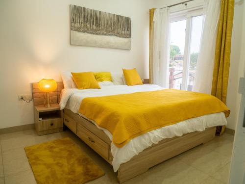 een slaapkamer met een bed met een geel dekbed en een raam bij Newly decorated 1 Bed Apartment, with balcony - Osu Residential in Christiansborg
