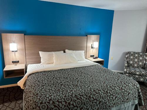 um quarto com uma cama grande e uma parede azul em Baymont by Wyndham Manistee em Manistee
