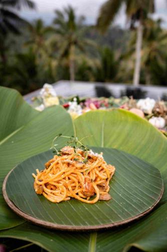 a plate of spaghetti on top of a green leaf at Amanuba Ersadeva Resort in Pulukan