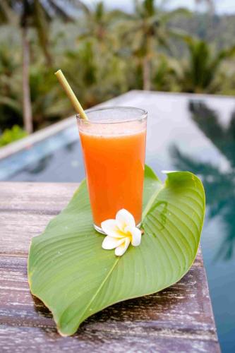 a drink on a banana leaf with a flower on it at Amanuba Ersadeva Resort in Pulukan