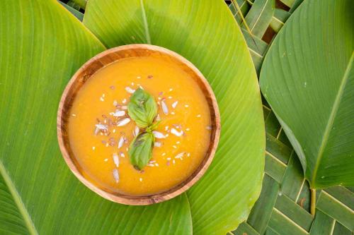 a bowl of orange soup on a large green leaf at Amanuba Ersadeva Resort in Pulukan