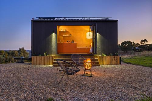 a black house with two chairs and a table at Sellicks Hill Eco Cabin - C21 SouthCoast Holidays in Sellicks Hill