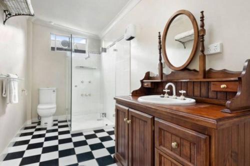 a bathroom with a sink and a mirror and a shower at The Hunter House c1917 in Cessnock
