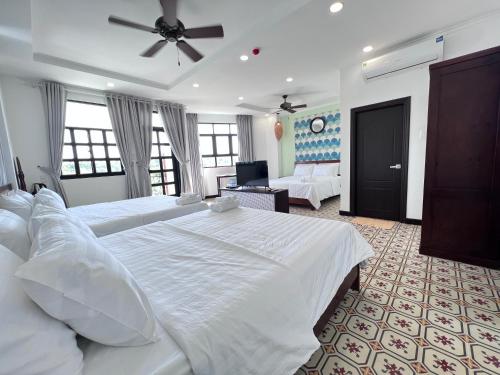 a large bedroom with two beds and a ceiling fan at Wanderlust Hotel in Mui Ne
