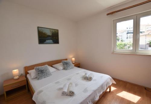 a bedroom with a white bed with towels on it at Apartments Zorana in Rogoznica