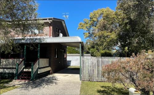 a house with a white fence and a gate at Namaste in Caboolture
