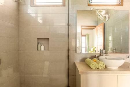 une salle de bain avec un lavabo et une douche avec un miroir dans l'établissement Villa Agung, à Nusa Lembongan
