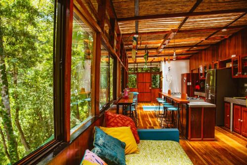 a living room with a couch and a kitchen with windows at Selva Madre Eco-Sanctuary in Cahuita