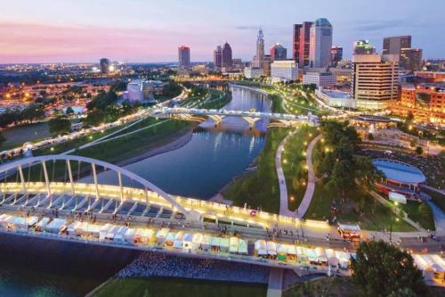 a bridge over a river with a city in the background at King & Queen in Downtown Columbus in Columbus
