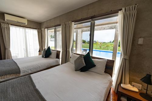 two beds in a room with a view of a pool at LEO Resort Sunayama in Miyako Island