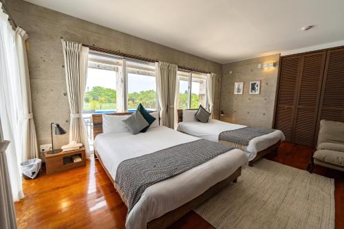 a bedroom with two beds and a large window at LEO Resort Sunayama in Miyako Island