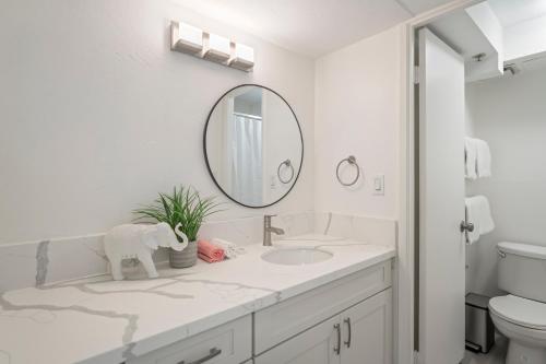 a white bathroom with a sink and a mirror at Hawaiian Monarch Penthouse 104 by Hawaii Ocean Club in Honolulu