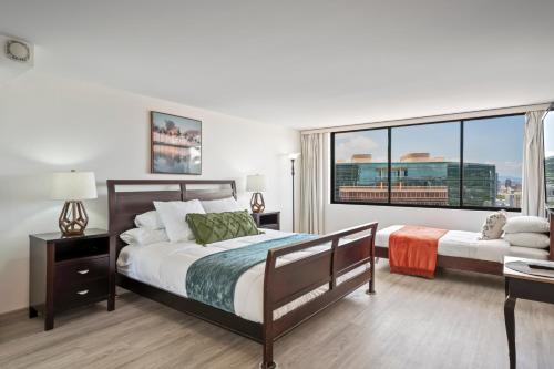 a bedroom with two beds and a large window at Hawaiian Monarch Penthouse 104 by Hawaii Ocean Club in Honolulu