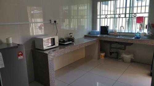 a kitchen with a counter with a microwave on it at Cozzy26 Homestay in Bintulu