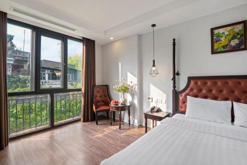 a bedroom with a bed and a chair and windows at 22land Residence Hotel 71 Hang Bong Premium in Hanoi