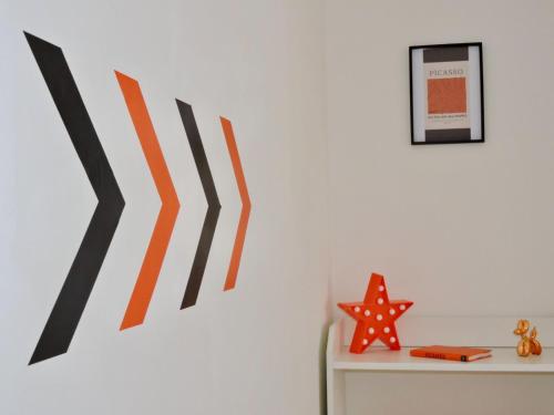 a white wall with orange and black artwork on it at Ty Pentref - Cwmcarn Village House in Cwmcarn