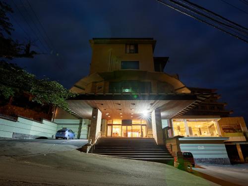 Tabist Izu Atagawa Onsen Hotel Gyokuryu في هيغاشيزو: مبنى امامه درج في الليل