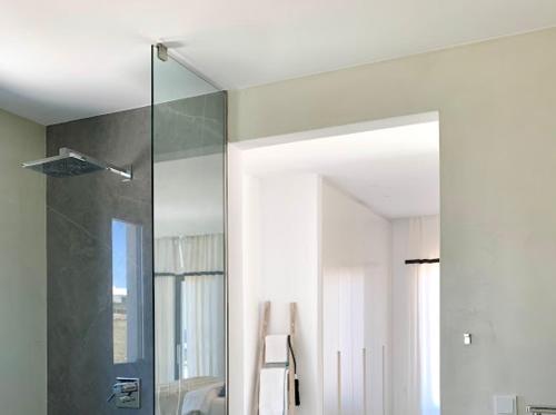 a bathroom with a glass shower and a mirror at Amalthea, Outstanding Seaside Luxury Villa, Paros in Santa Marina
