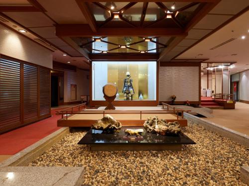 een grote kamer met een standbeeld in het midden bij Tabist Izu Atagawa Onsen Hotel Gyokuryu in Higashiizu